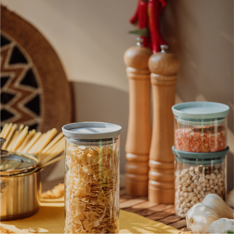 Pasta, grains, garlic and kitchen ingredients arranged on a countertop.