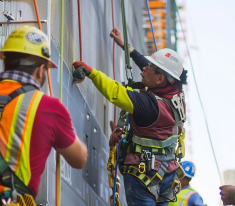 Workers wearing protective helmets and harnesses at a worksite.