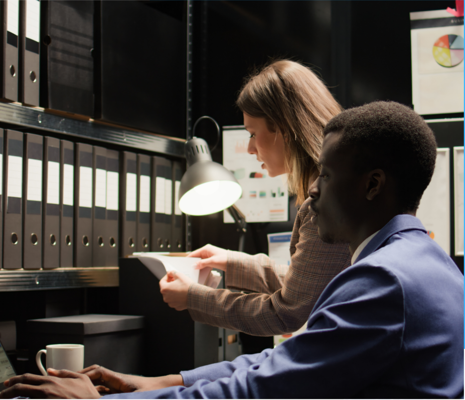 Two colleagues reviewing documents beside shelves of folders.