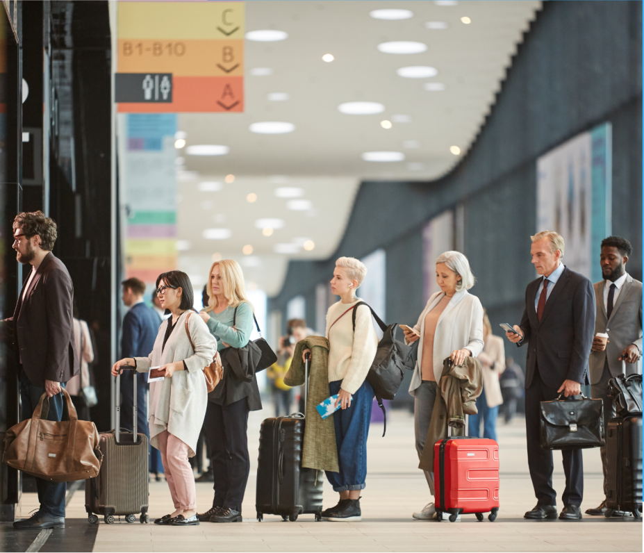 Passengers with luggage waiting inside an airport terminal.